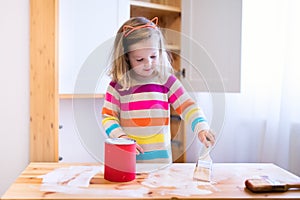 Little girl painting wooden closet