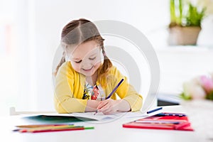 Little girl painting and writing