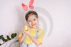 Little girl paints and glues stickers on eggs