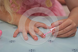 a little girl paints her nails,the girl does a manicure on her hands