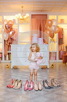 A little girl in pajamas put on high-heeled shoes for mom. The child is measuring his mother`s shoes