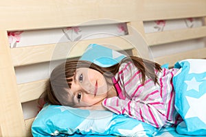 Little girl in pajamas sleep in bed under a blue blanket