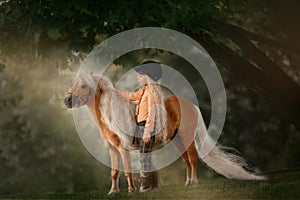 Little girl with palomino miniature horse in summer day