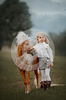 Little girl with palomino miniature horse in summer day