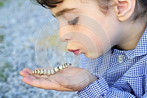 Little girl palying with silkworm in hands