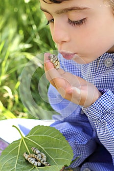 Little girl palying with silkworm in hands