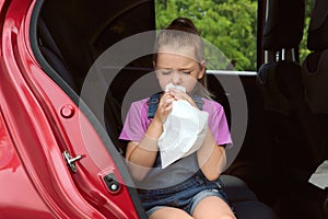 Little girl with paper bag suffering from nausea in car photo