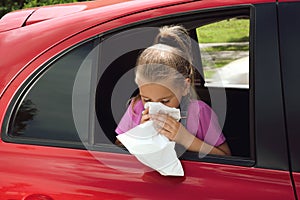 Little girl with paper bag suffering from nausea in car