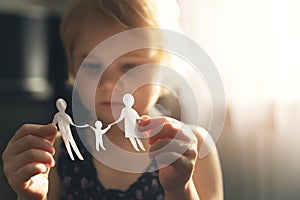 Little girl with paper family in hands. concept of divorce, custody and child abuse