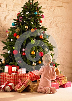 Little girl with parcels round Christmas tree photo