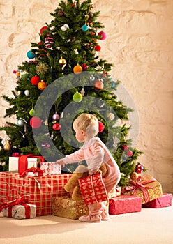 Little girl with parcels round Christmas tree photo
