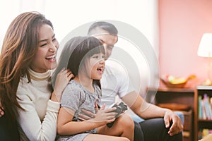 Little girl and parent family playing video game at home.