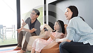 Little girl and parent family playing video game at home.