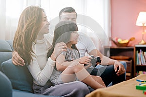 Little girl and parent family playing video game at home.