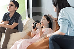 Little girl and parent family playing video game at home.