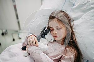 Little girl patient lying in hospital bed. Children in intensive care unit in hospital sleeping.