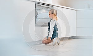 Little girl patiently waiting in front of her oven. Caucasian child waiting for her baked food. Blonde little girl
