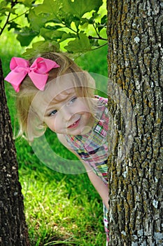 Little girl peaking around tree photo