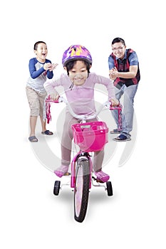 Little girl pedaling bicycle with family