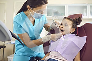 Little girl at a pediatric dentist with mask and gloves service child tooth care in a dental dentistry clinic. photo