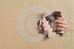 Little girl peeking from a hole on cardboard box.