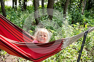 Little girl peeking out of a red hammock