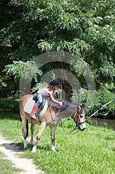 Little girl petting a horse while horseback riding