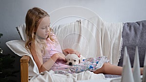 Little Girl Petting Puppy on Sofa in Christmas