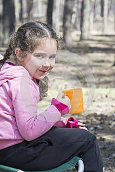 Little girl petting tea or juice during a halt in the forest