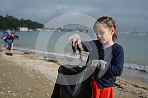 Little girl pick up rubbish from the beach photo