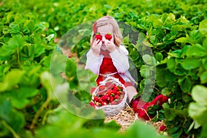 Little girl picking strawberry on a farm field