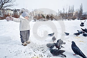 Little girl and pigeons in winter.