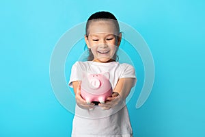 Little girl with piggy bank, studio shot, copy space