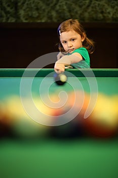 Little girl with pigtails starts the game of pool
