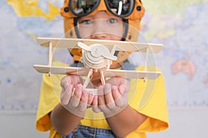 Little girl in a pilot hat holding a toy plane in her hands having fun in kids room at home. Happy child girl at home dreaming of