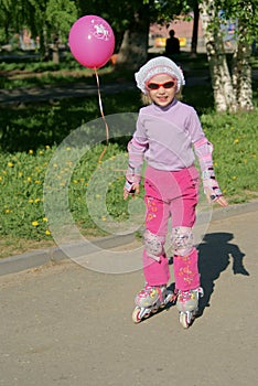 Little girl with pink balloon riding on roller blades