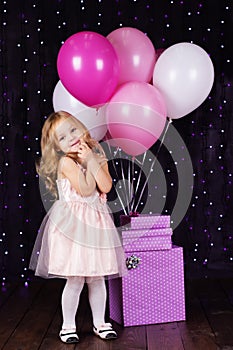 Little girl with pink balloons and gift boxes