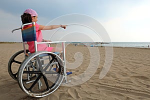 Little girl with pink bandana on the head on the beach on the wh