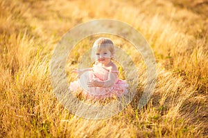 Little girl pink dress sit on sloping  wheat field