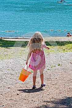 Little girl pink dress walking near beach