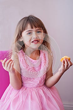 Little girl in pink fancy dress, eating sweet cupcake