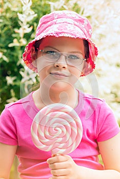 Little girl in a pink hat holding lollipop