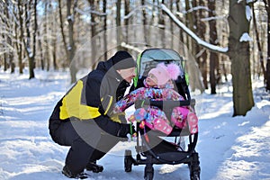 A little girl in a pink hat and overalls for a walk in the woods on a winter snowy