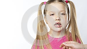 Little girl in pink holds with a thread on a milk tooth