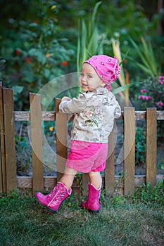 Little girl in pink shoes near the fence
