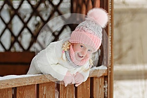 A little girl in a pink skirt in winter smiles in a park in a ga