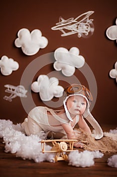 Little girl in a pink white suit and a pilot`s hat with white clouds and painted airplanes