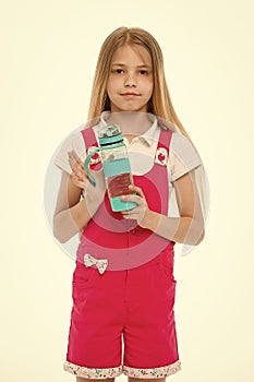 Little girl with plastic bottle isolated on white. Thirsty child in pink jumpsuit hold water bottle. Drinking water for