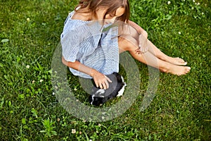 A little girl play with Black Guinea pig sitting outdoors in summer