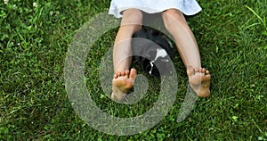 A little girl play with Black Guinea pig sitting outdoors in summer